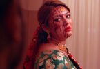 Barsha Raut in a bridal outfit, looking over her shoulder with blood marks on her face in a tense scene from the short film Missing Bride.