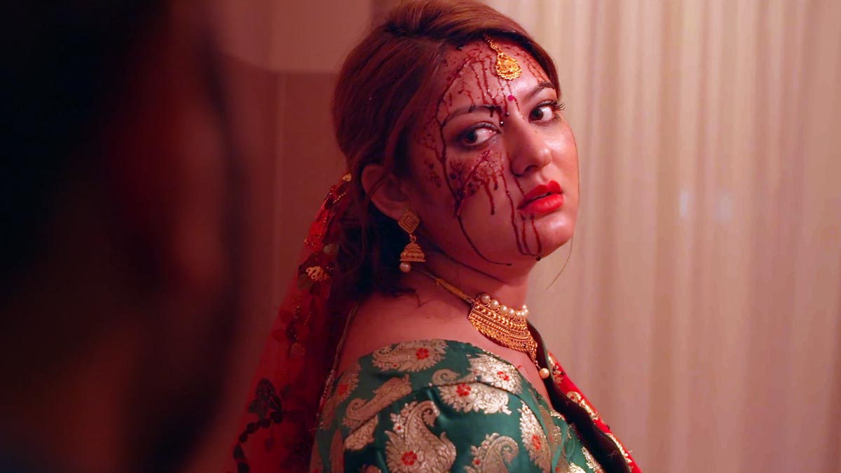 Barsha Raut in a bridal outfit, looking over her shoulder with blood marks on her face in a tense scene from the short film Missing Bride.